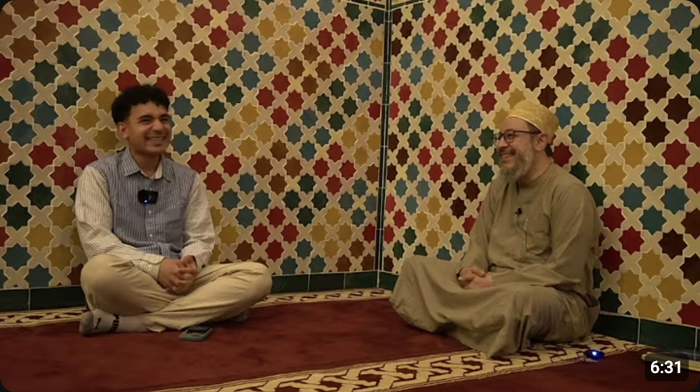 Behind the Imam, episode 1: Aslam sitting with Shaykh Ahmad Saad in a tiled mosque room